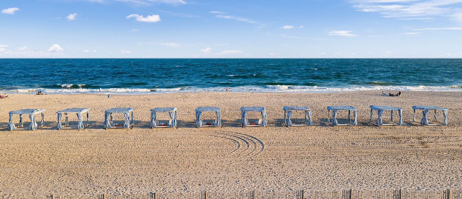 A beach with striped beach chairs lined up in a row.
