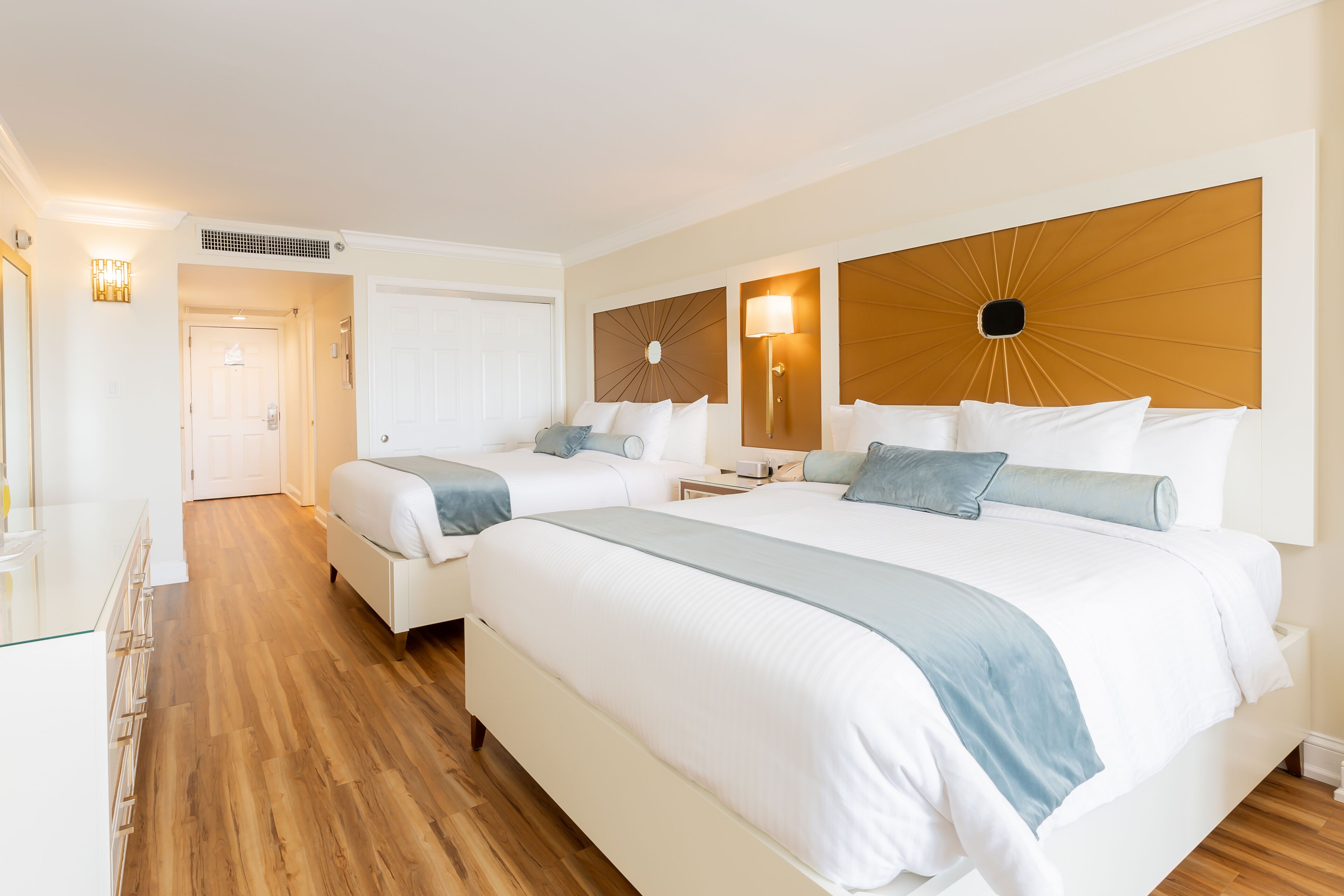 Ein Hotelzimmer mit zwei Betten, einem Glastisch und einem Holzboden.