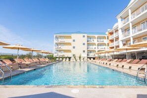 Una piscina al aire libre de temporada, sombrillas, tumbonas