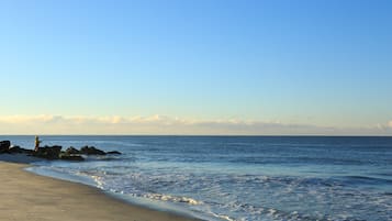 A beach with rocks and a person fishing.