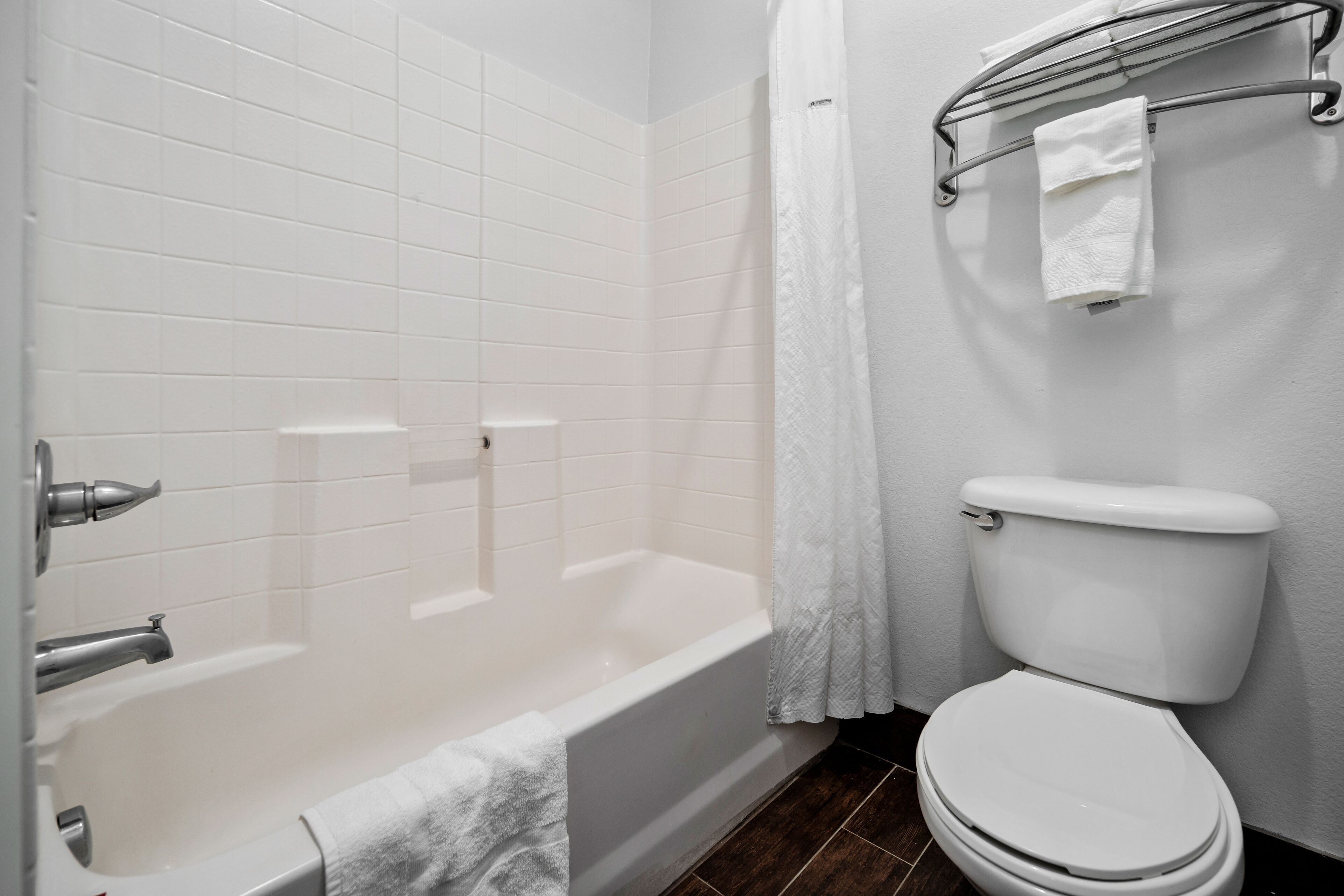 A bathroom with a bathtub, toilet, and a towel rack.