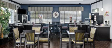 A modern kitchen with a dining area, featuring a central clock, striped window treatments, and a coffee machine.