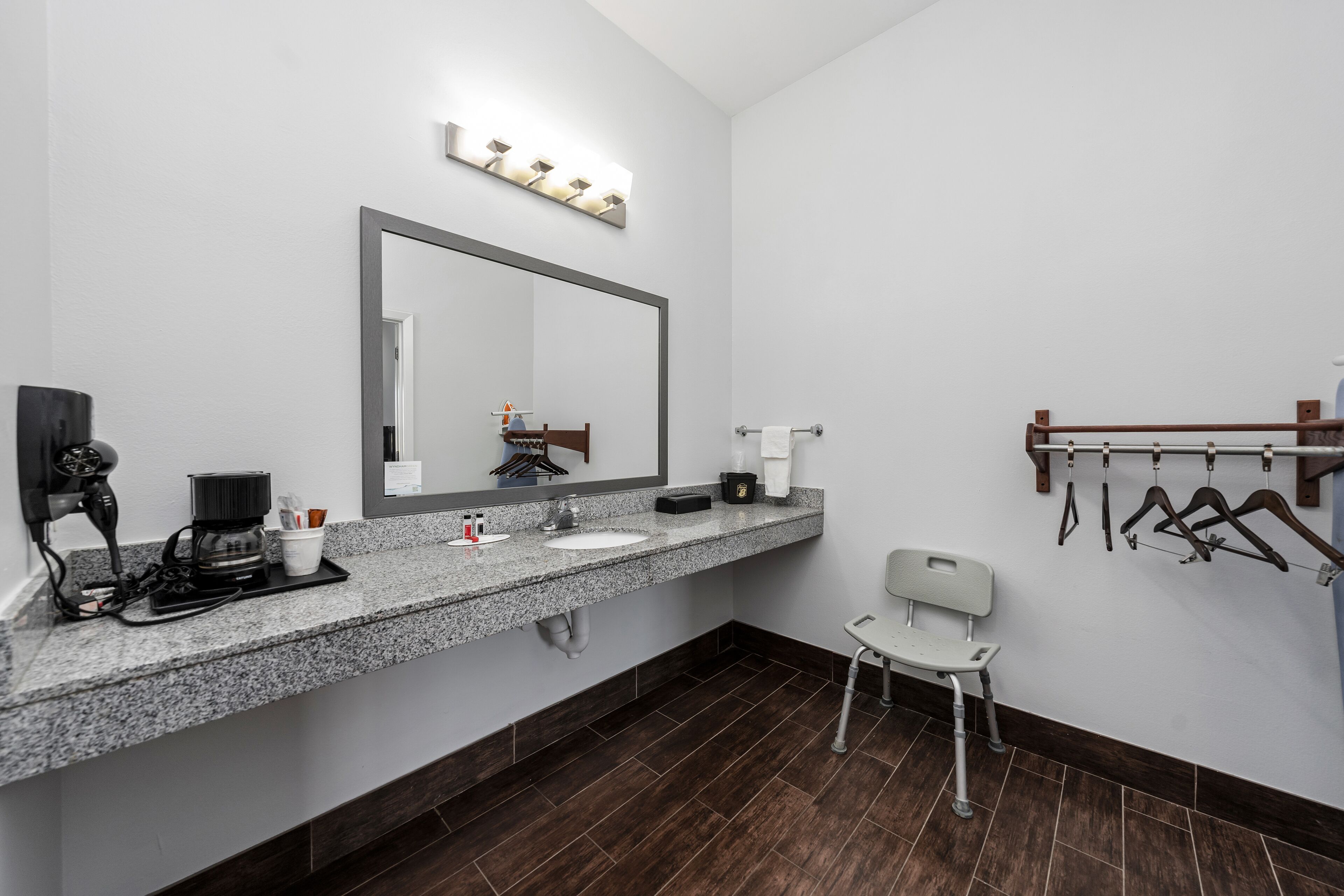 Une salle de bain moderne avec un comptoir en granit, un grand miroir, une machine à café et un porte-serviettes.
