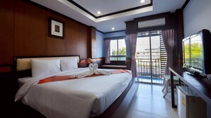 A hotel room with a large bed, a desk with a computer, a window with curtains, and a balcony with a view. - Season Palace Huahin Hotel (Cha-am)