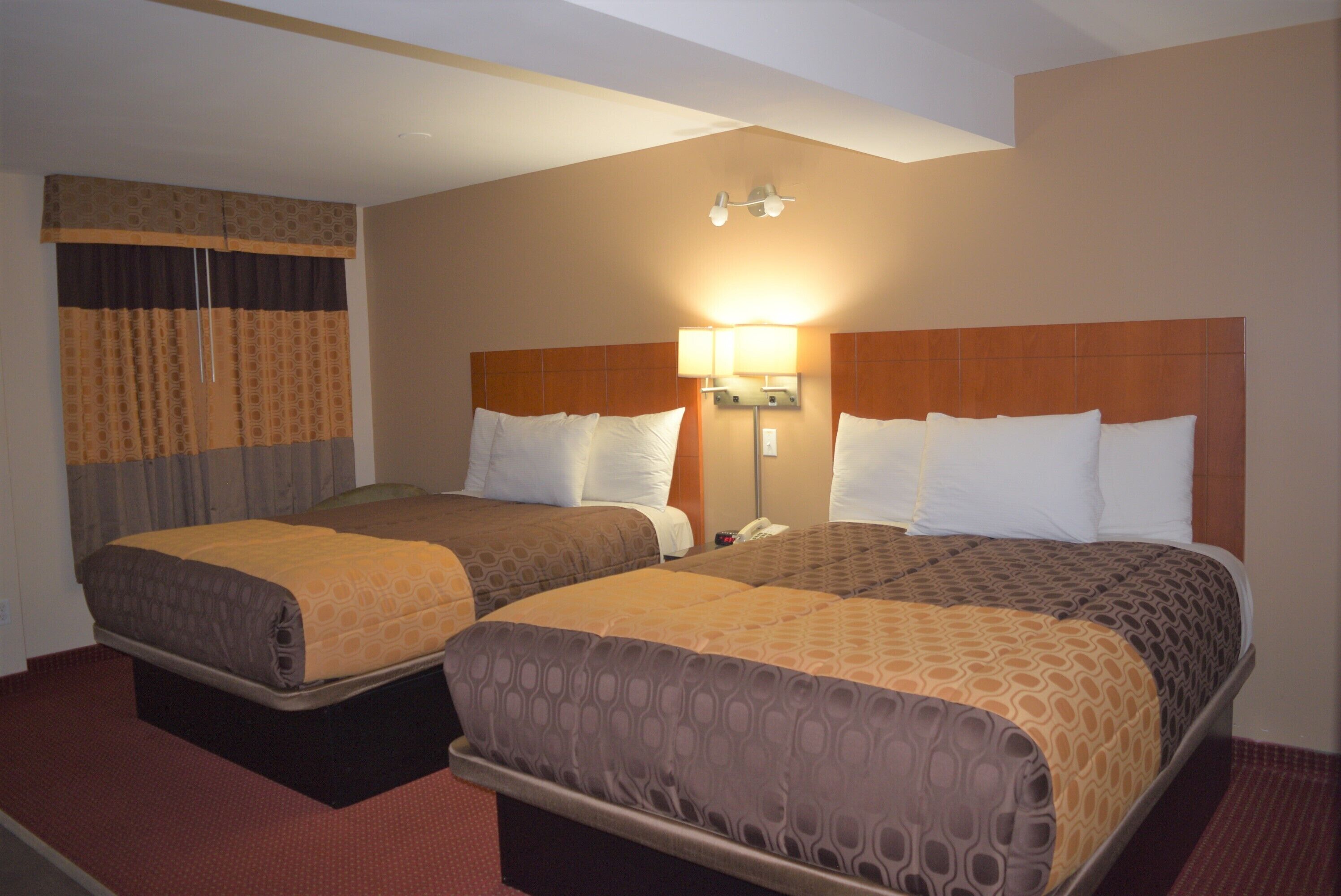 A hotel room with two beds, a wardrobe, and a bedside lamp.