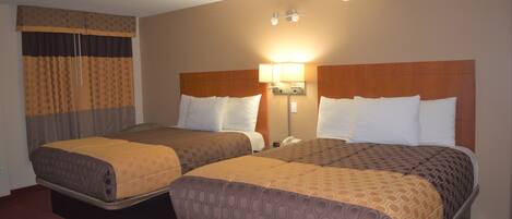 A hotel room with two beds, a wardrobe, and a bedside lamp.