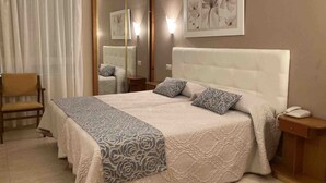 A hotel room with a large bed, a chair, a bedside table, a mirror, and a wall-mounted artwork. - Hotel El Refugio (Alfoz de Lloredo)