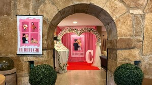 An archway leading to a wedding reception area with a red carpet, floral decorations, and a large 'C' sign. - Hotel El Refugio (Alfoz de Lloredo)
