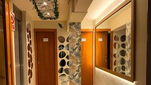 A hallway with a marble floor, wooden doors, and a large mirror with circular patterns. - Hotel El Refugio (Alfoz de Lloredo)