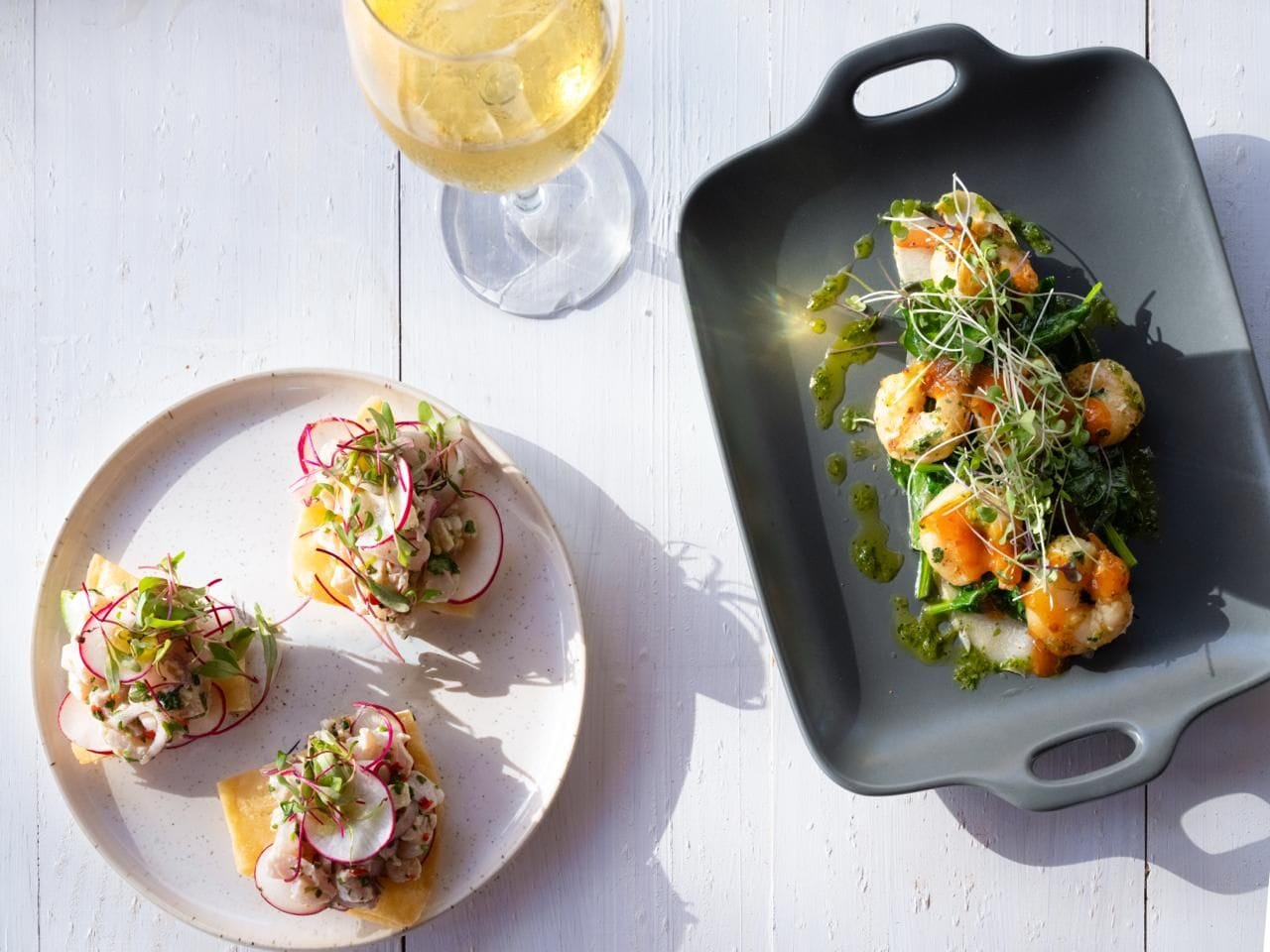 A dining table with plates of food and a glass of wine.