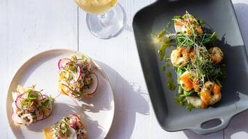A dining table with plates of food and a glass of wine.