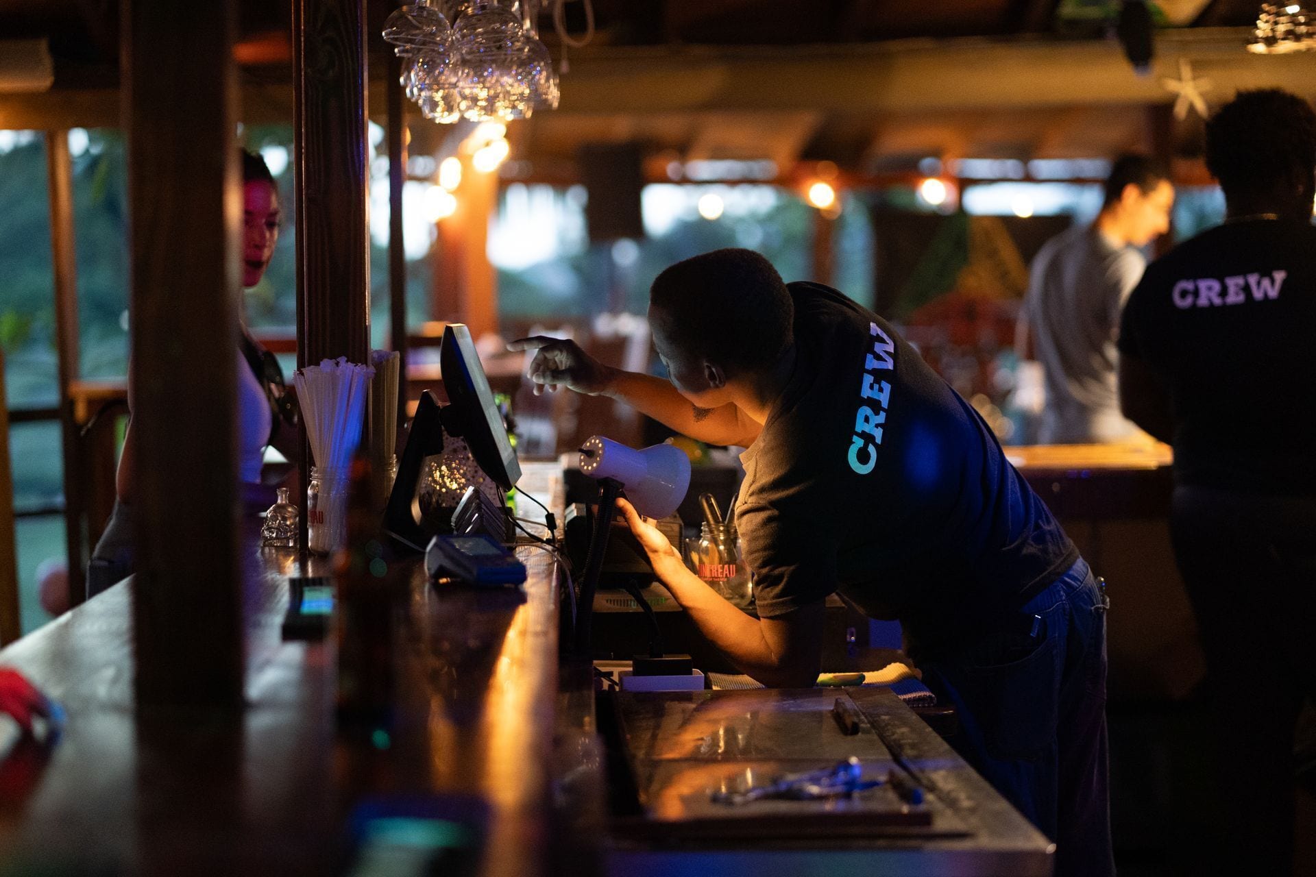 Un bartender trabajando en un bar con poca luz.
