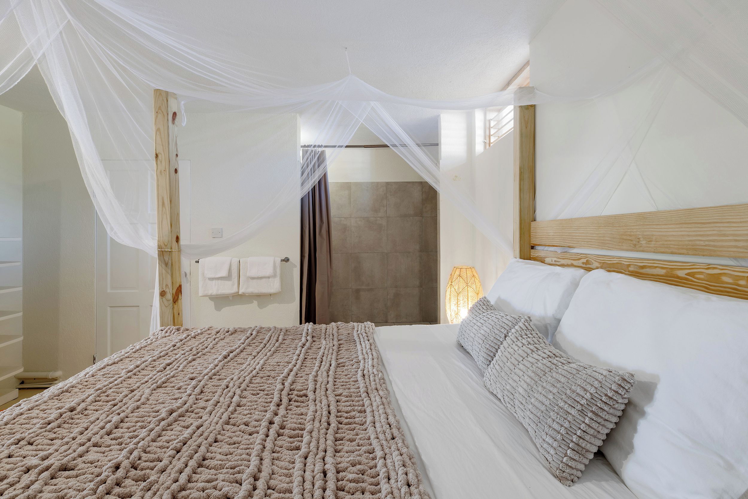 A bedroom with a bed, a wooden headboard, a bedside lamp, and a canopy.
