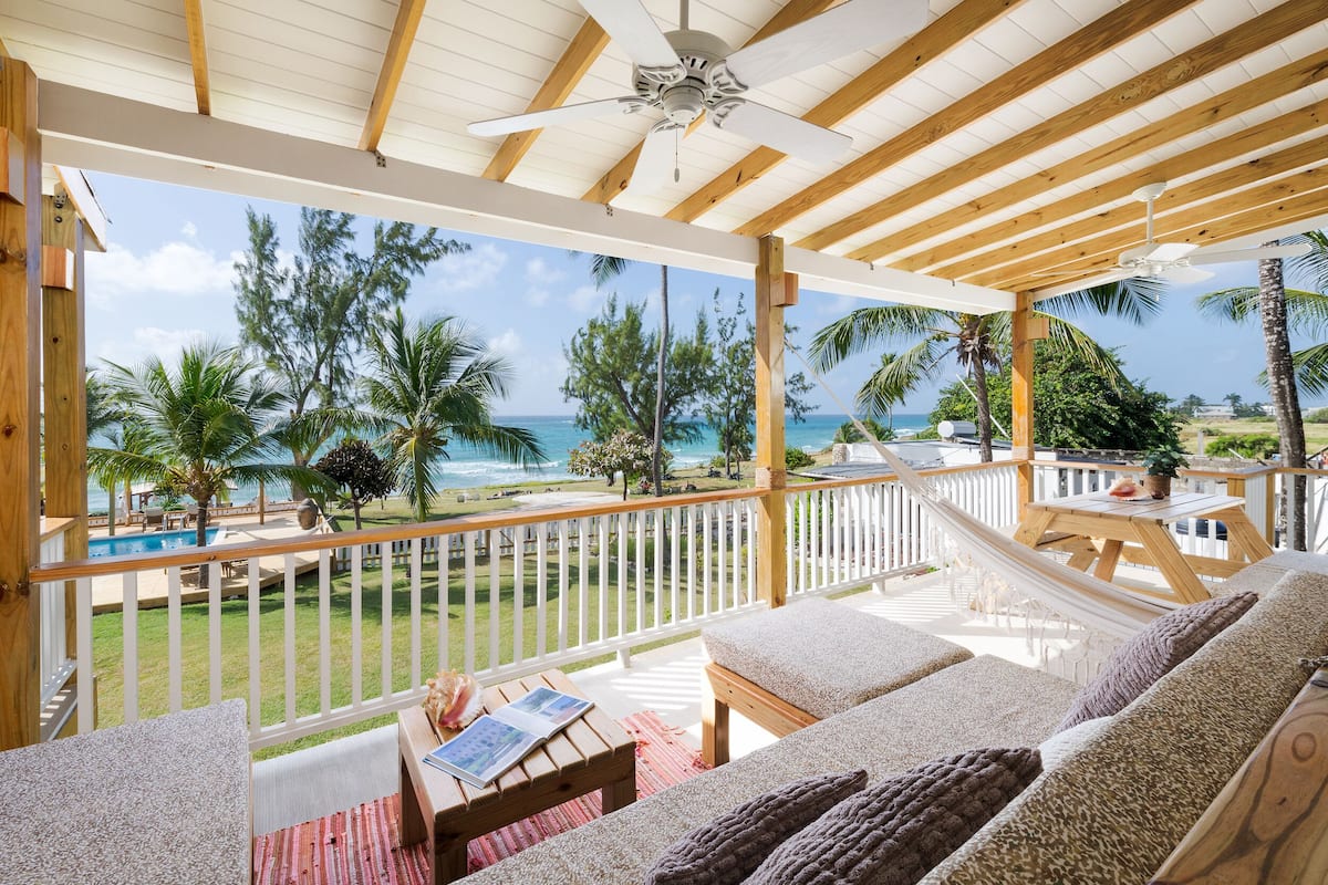 A covered outdoor area with a hammock, lounge chairs, and a pool view.