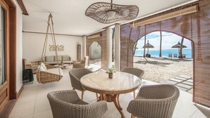 A beachside room with wicker furniture, a round table, and a hanging chair. - Paradis Beachcomber Golf Resort & Spa (Le Morne)