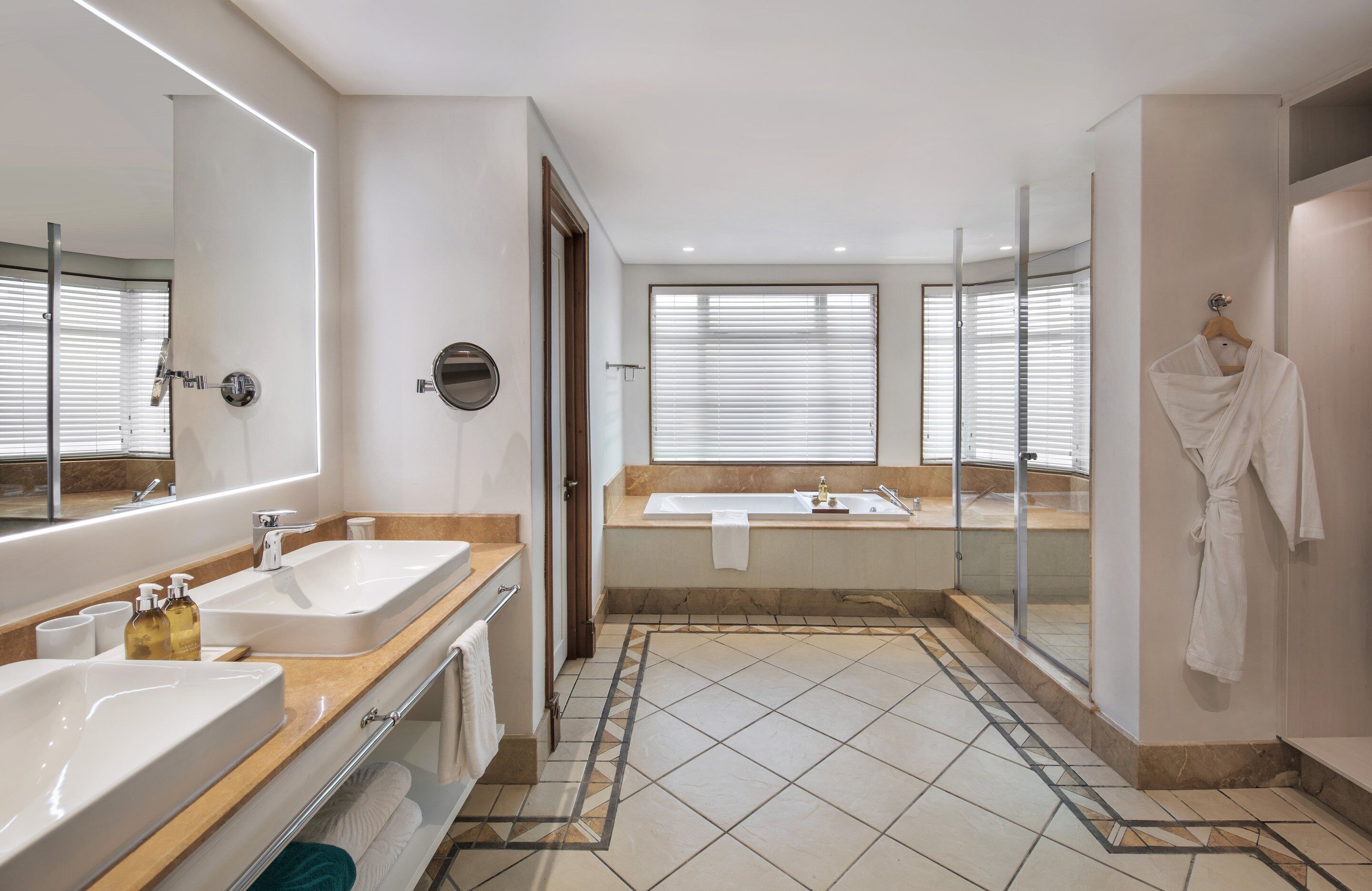 A modern bathroom with two sinks, a bathtub, and a glass shower enclosure.