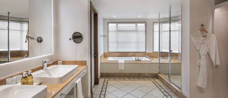 A modern bathroom with two sinks, a bathtub, and a glass shower enclosure.