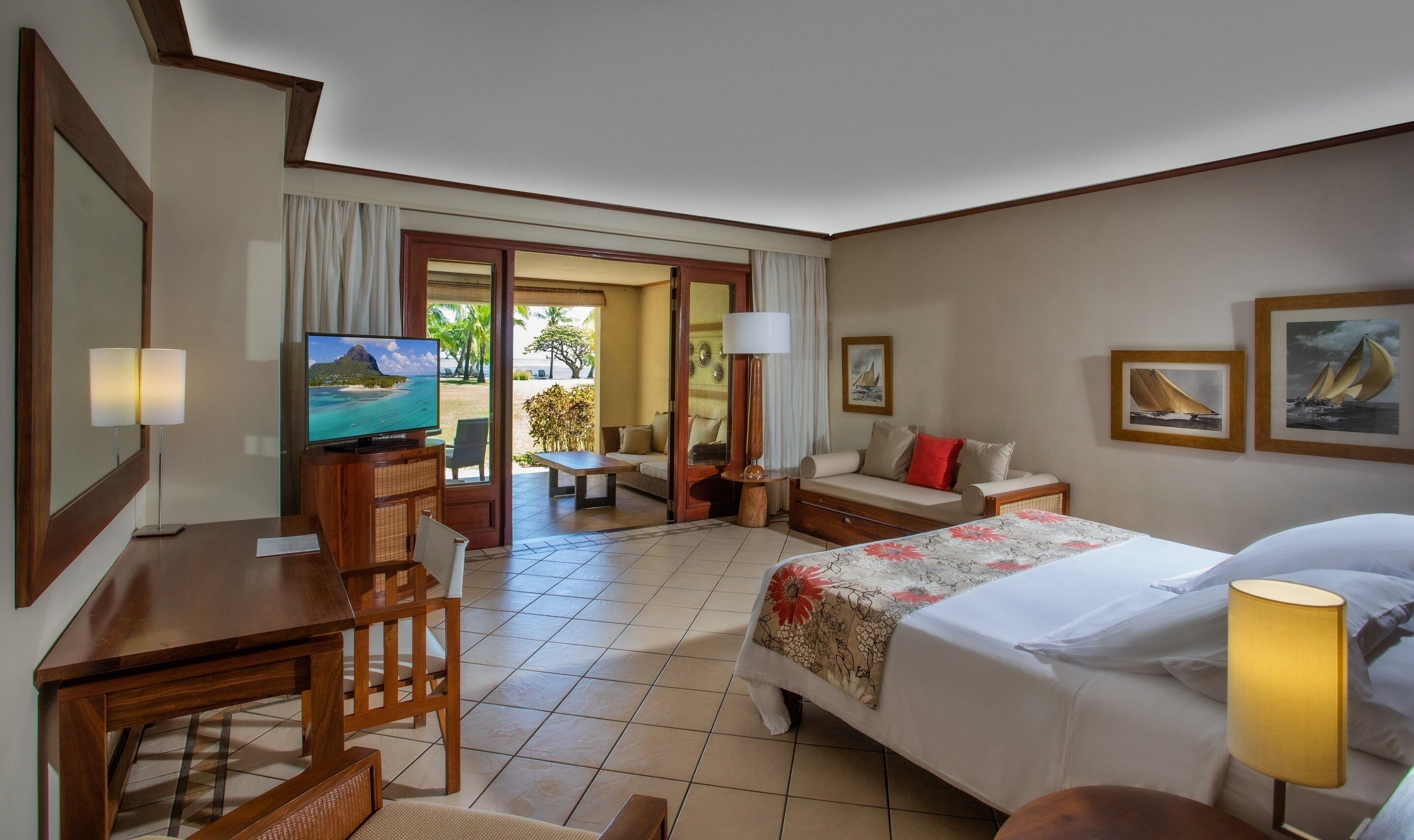 Habitación de hotel con cama, escritorio con televisor, sofá y vista al exterior.