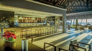 A bar area with a view of the ocean, wooden furniture, and a thatched roof structure. - Paradis Beachcomber Golf Resort & Spa (Le Morne)