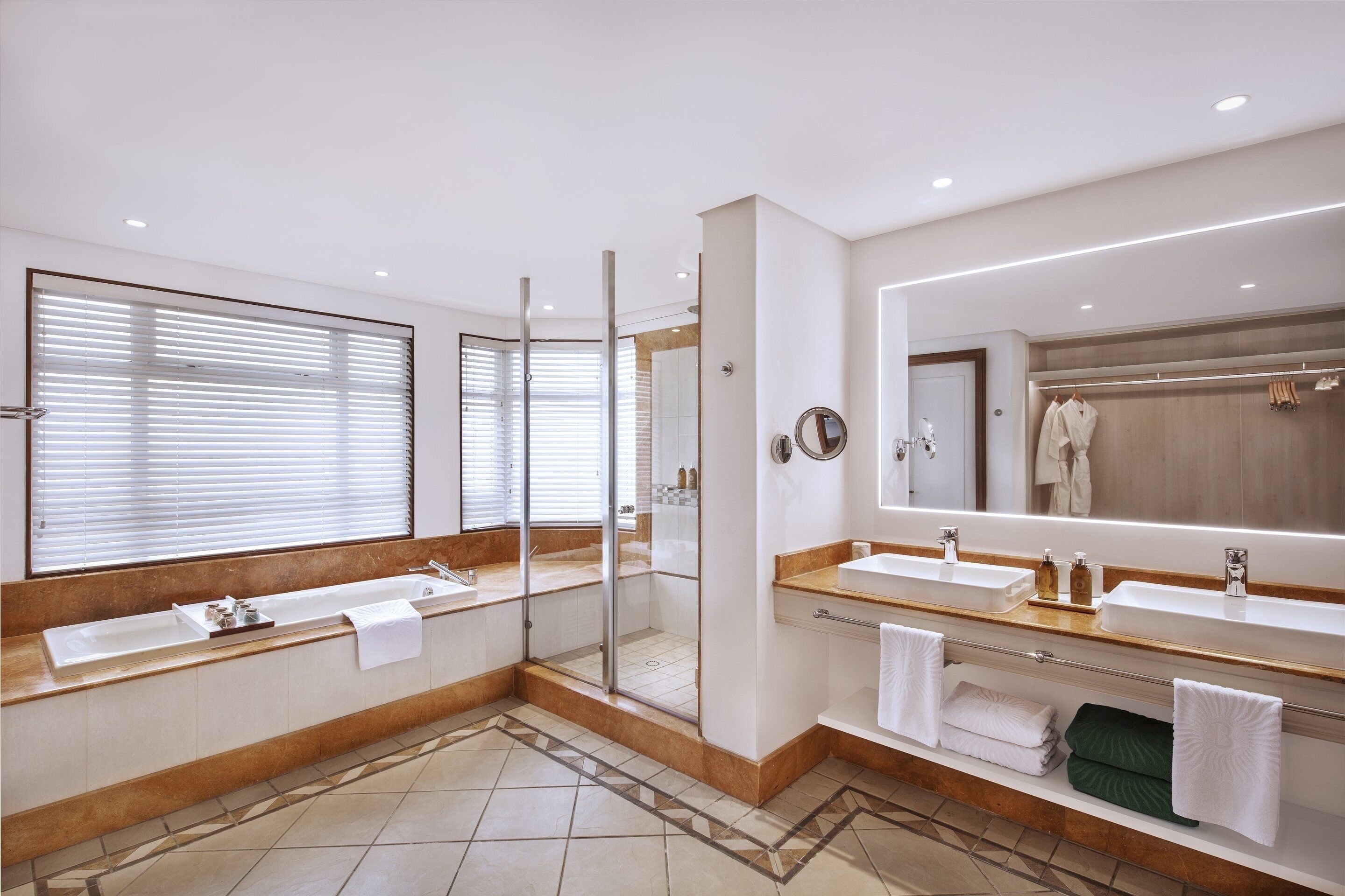 Un baño moderno con dos lavamanos, ducha a ras de suelo y un espejo grande.