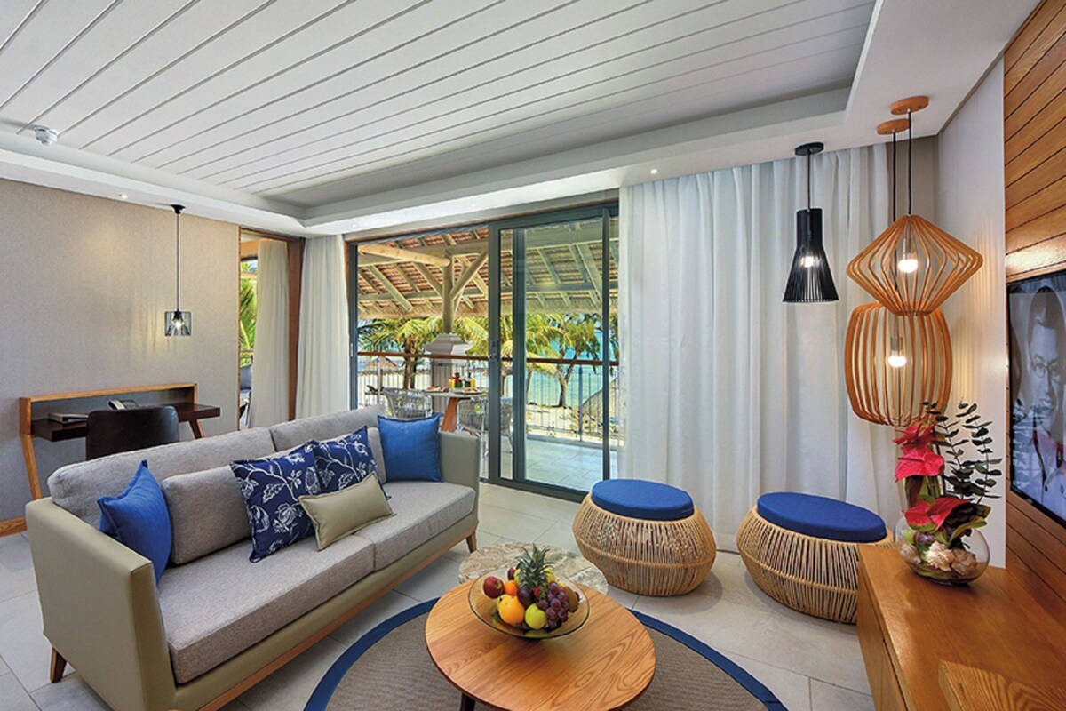 A modern living room with a sofa, coffee table, and two wicker stools.