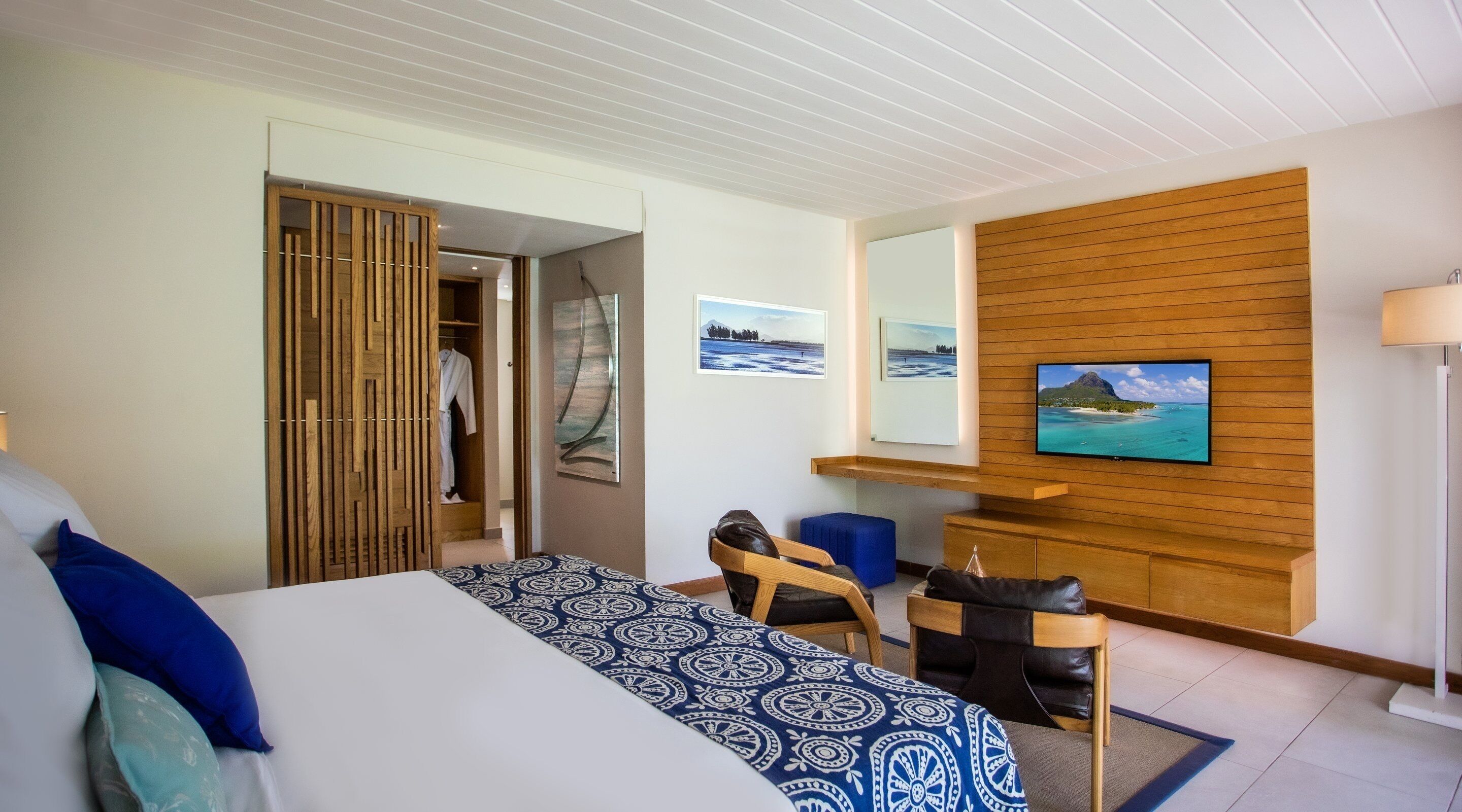 Une chambre d’hôtel comprenant un lit, un bureau, une chaise, un téléviseur fixé au mur (qui est en bois) et une armoire.