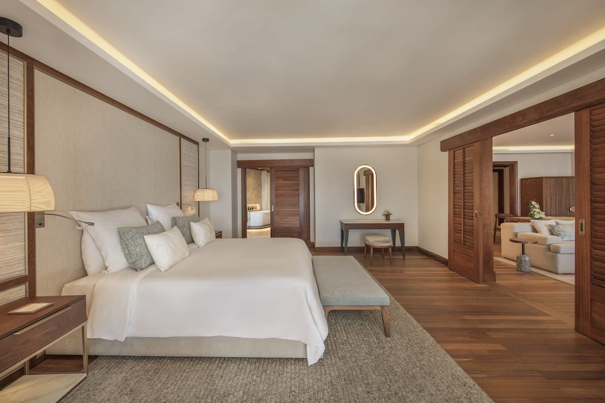 A modern hotel room with a large bed, bedside tables, a desk, and a seating area.