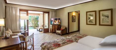 Habitación de hotel con cama, escritorio, silla, televisión y vista al exterior.