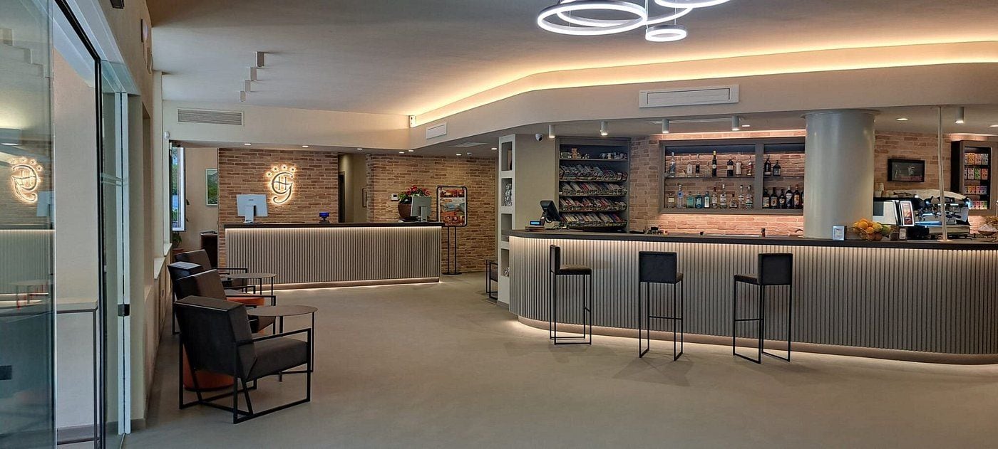 A modern bar area with a curved counter, bar stools, and a reception desk with a logo.