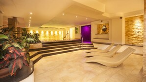 Ein Spa-Bereich mit Steinwand, einem violett beleuchteten Raum und einer Treppe zu einer höheren Ebene.