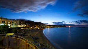 Ein Küstenhotel mit Blick auf den Strand, einer Uferpromenade und einem Bergpanorama.