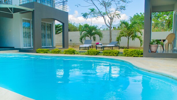 A swimming pool with lounge chairs and a potted plant. - Mo Residence (Grand-Baie)
