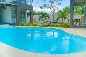 A swimming pool with lounge chairs and a potted plant. - Mo Residence (Grand-Baie)