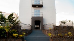 A building with a central entrance, stone steps, and metal railings. - Mo Residence (Grand-Baie)