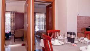 A hotel room with a dining area, a bed, and a bathroom visible through an open door. - Mo Residence (Grand-Baie)