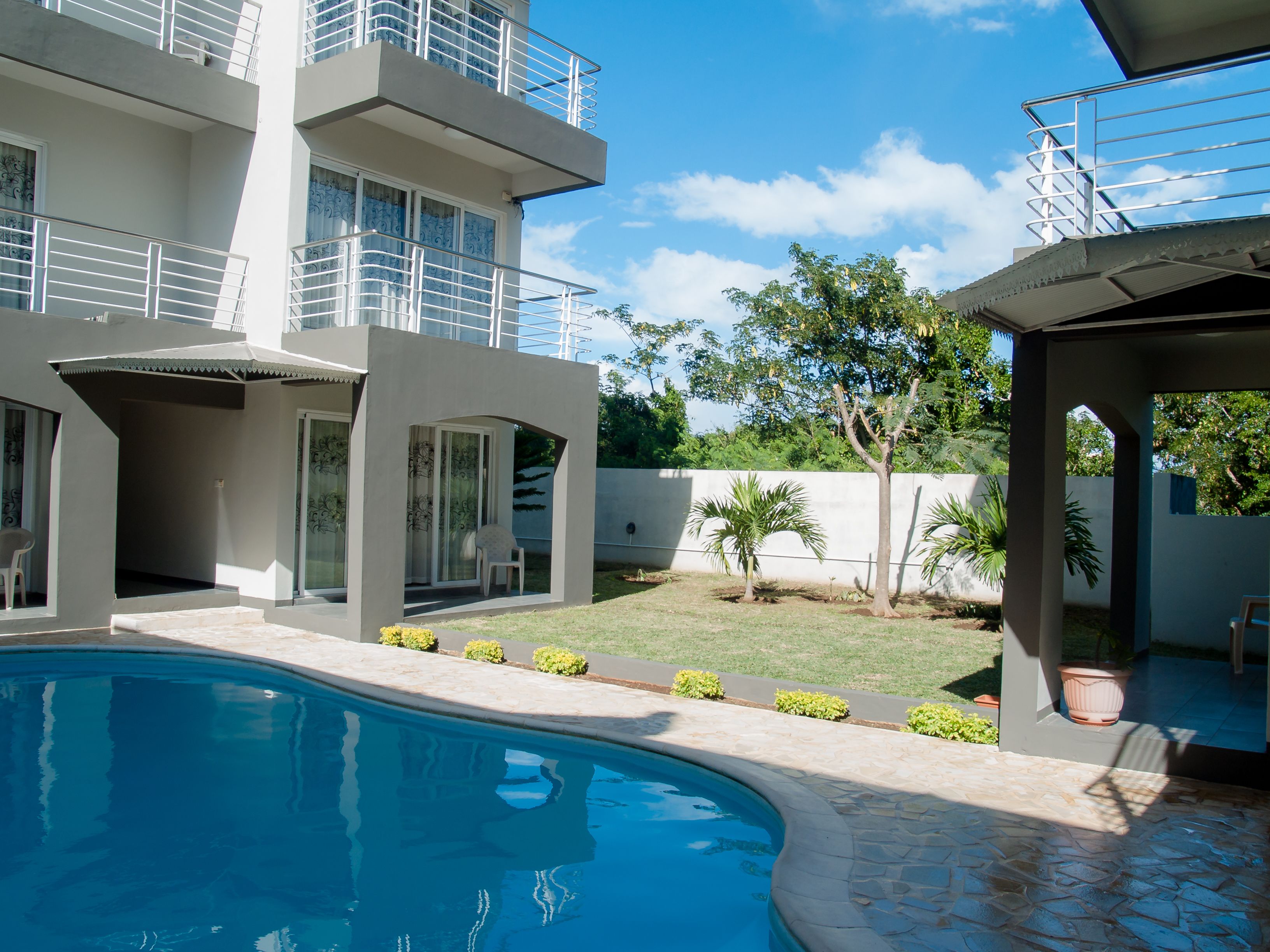 A modern building with a swimming pool, outdoor seating, and a covered area.