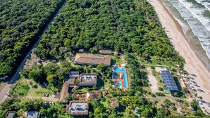An aerial view of a coastal property with a swimming pool, solar panels, and a beach. - Ilhéus North Hotel (Uruçuca)