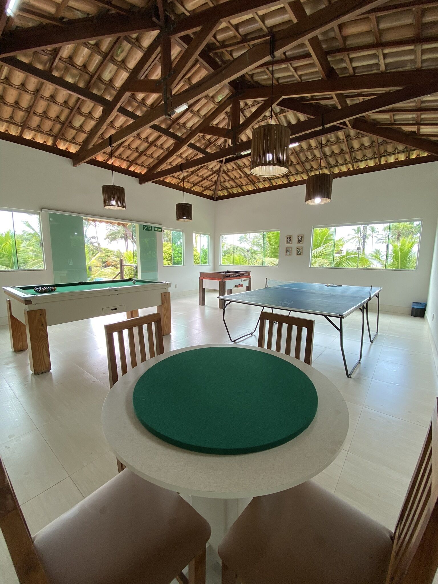Een ruime kamer met een pooltafel, een tafelvoetbaltafel en een pingpongtafel.