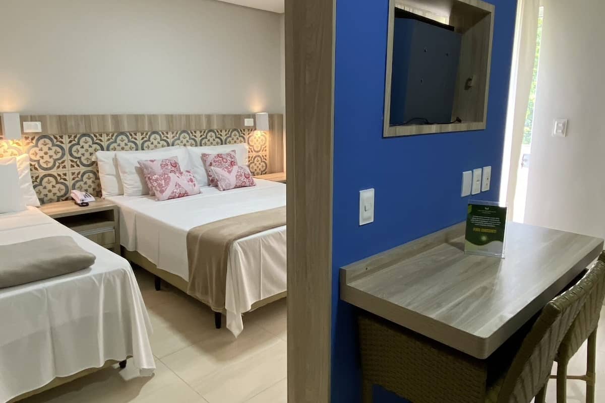 A hotel room with two beds, a desk, and a chair.
