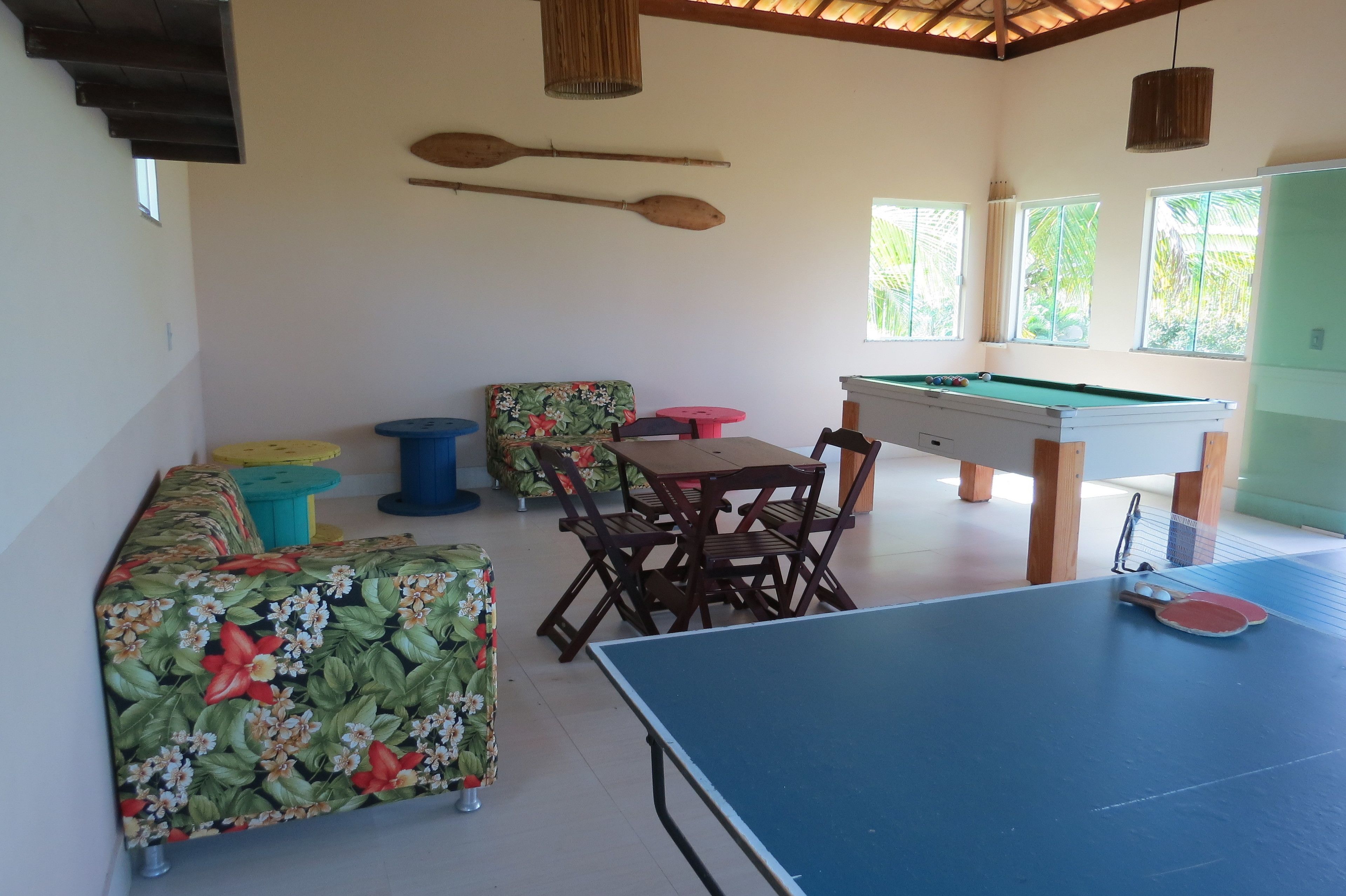 Una habitación con mesa de billar, piscina y mesa con sillas.