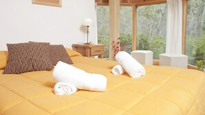 A bed with a yellow quilt, two rolled towels, and patterned pillows. - Rucaleufú Apart Hotel y Cabañas (San Martín de los Andes)