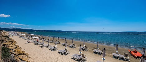 Een privéstrand, ligstoelen aan het strand, parasols, strandlakens