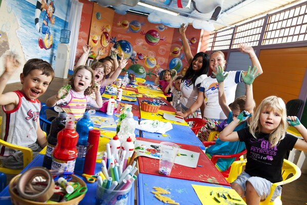 A group of children engaged in a painting activity with art supplies spread across a table. - Hotel Golfo del Sole (Follonica)