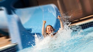 Eine Person im Schwimmbecken, umgeben von spritzendem Wasser.