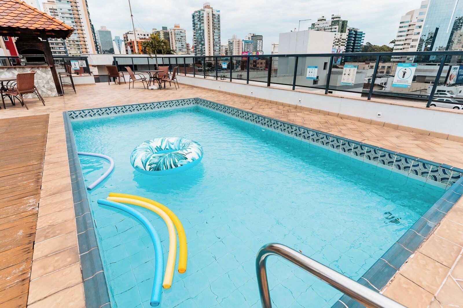 A rooftop pool with a view of the city skyline, a barbecue area, and a seating arrangement.