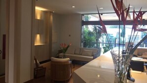 Un moderno vestíbulo de hotel con un ventanal grande, un mostrador de recepción, un sofá y un jarrón decorativo con flores rojas.