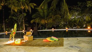 An outdoor area with a pool, lounge chairs, and a tiki bar setup. - Pousada Jacarandá (Porto Seguro)