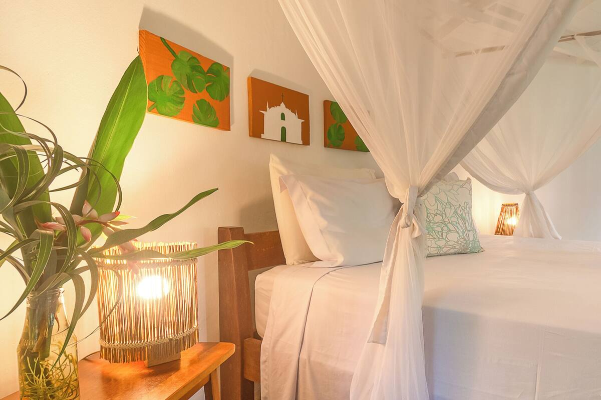 Ein Schlafzimmer mit einem Bett, einem Nachttisch mit Lampe und Wandbildern.