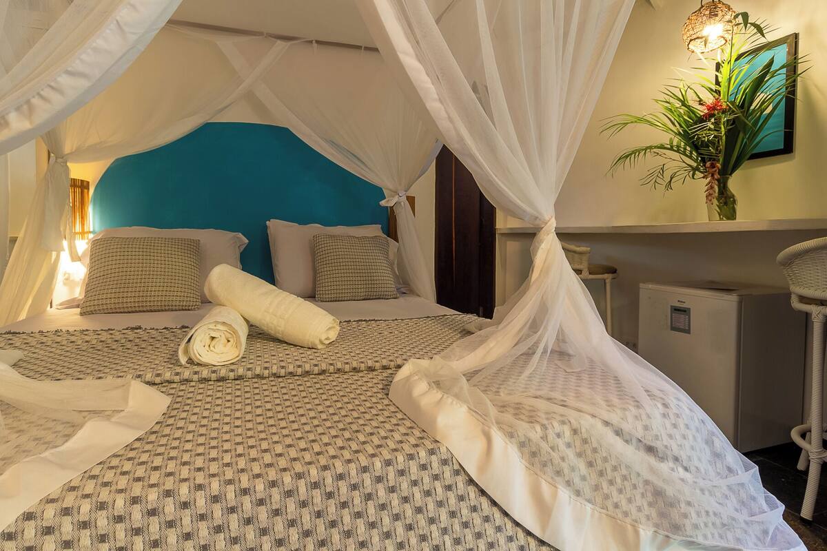 Ein Schlafzimmer mit einem Himmelsbett, einer blauen Akzentwand und einem Nachttisch mit Lampe.