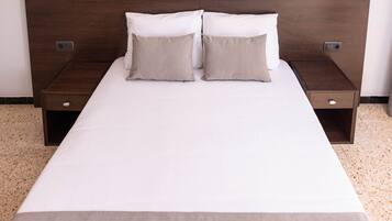 A double bed with a wooden headboard, two nightstands, and a drawer.